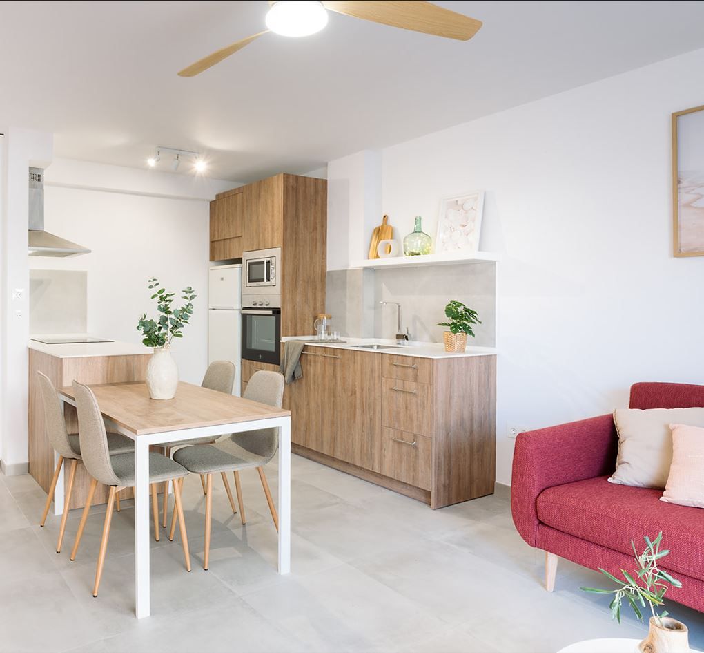 Cocina integrada en salón con diseño minimalista y detalles cálidos de interiorismo evolutivo